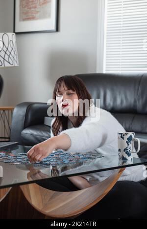 Frau tut Puzzle auf Couchtisch