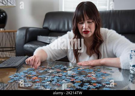 Frau tut Puzzle auf Couchtisch