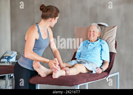 Ihre Patienten dabei zu unterstützen, stark und gesund zu bleiben. Eine Physiotherapeutin, die mit einem älteren Mann zusammenarbeitet. Stockfoto