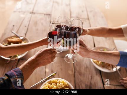 Heres zu guten Zeiten mit tollen Menschen. Menschen toasten mit Wein bei einer Mahlzeit. Stockfoto