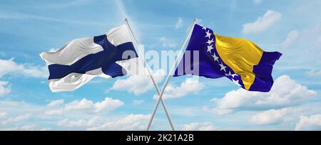 Zwei gekreuzte Flaggen Bosnien und Herzegowina und finnland winken im Wind bei bewölktem Himmel. Konzept der Beziehung, des Dialogs, des Reisens zwischen zwei Ländern. Stockfoto