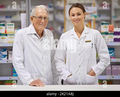 Er kennt die Medizin. Ein älterer Apotheker und ein junger Apotheker stehen an der Theke. Stockfoto