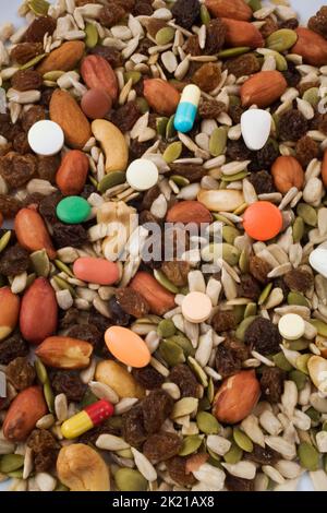 Getrocknete Früchte und Nüsse gemischt mit Arzneipillen. Stockfoto