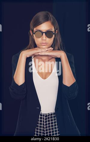 Shes hat einen eigenen Stil. Beschnittene Studioaufnahme einer schönen jungen Frau mit dem Kopf auf den Händen. Stockfoto