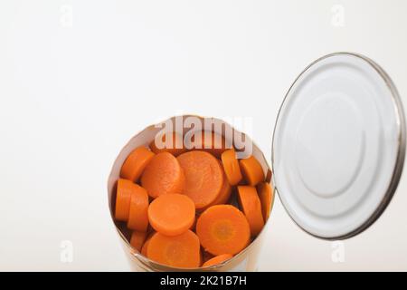 Nahaufnahme von in Scheiben geschnittenen Karotten in Blechdose auf weißem Hintergrund. Stockfoto