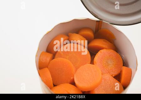 Nahaufnahme von in Scheiben geschnittenen Karotten in Blechdose auf weißem Hintergrund. Stockfoto