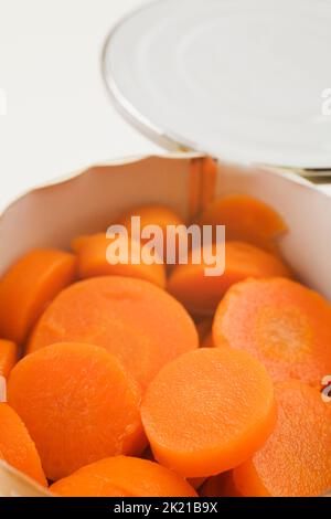 Nahaufnahme von in Scheiben geschnittenen Karotten in Blechdose auf weißem Hintergrund. Stockfoto