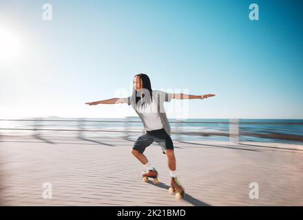 Man Rollschuhlaufen auf der Strandpromenade während eines Sommerurlaubs zum Spaß und zur Bewegung. Jung, fit und gesund Kerl Skaten für eine Fitness Stockfoto