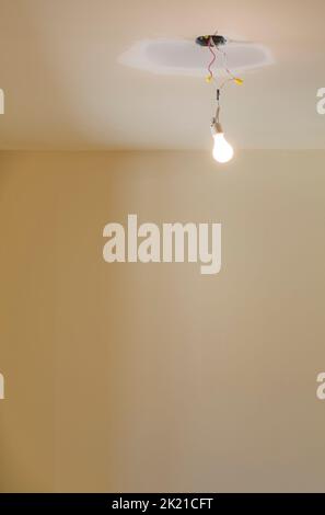 Glühlampe, die an der Decke hängt, Gipskarton wird im Haus repariert. Stockfoto