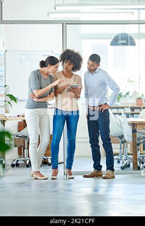 Gleichgesinnte Kreative. Eine Gruppe von Bürokollegen, die über ein digitales Tablet diskutieren. Stockfoto