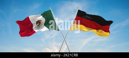 Zwei gekreuzte Flaggen der Bundesrepublik Deutschland und mexikos winken im Wind bei bewölktem Himmel. Konzept von Beziehung, Dialog, Reisen zwischen zwei Countri Stockfoto