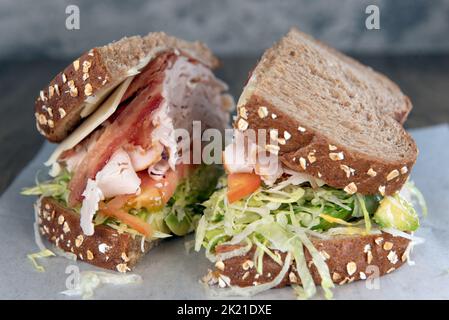 Das Mittagessen wird mit einem beladenen truthahn, Speck und einem Avocado-Sandwich serviert, das mit Zutaten überfüllt ist. Stockfoto