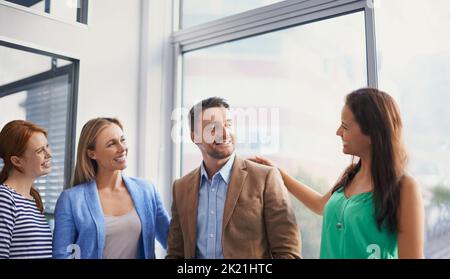 Eine Gruppe von Geschäftsfrauen gratulierte ihrem Kollegen zu seinem Job Gut gemacht. Stockfoto