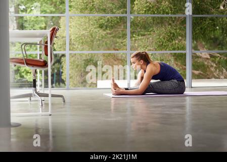 Yoga ist der Schlüssel zur Gesundheit. Ganzkörperaufnahme einer sportlichen Frau, die zu Hause Yoga praktiziert. Stockfoto