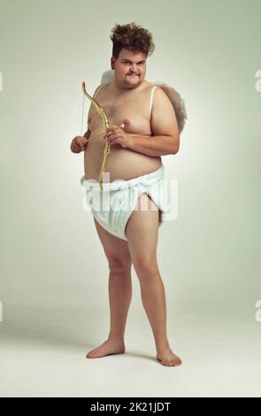 Hes bringt die Liebe dieses Valentines. Ein übergewichtiger Mann, der als Cherub mit Pfeil und Bogen gekleidet ist. Stockfoto