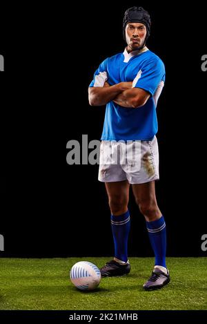 Lasst mich sehen, dass Ihr mir diesen Ball wegnehmt. Ein junger Rugby-Spieler auf dem Spielfeld. Stockfoto