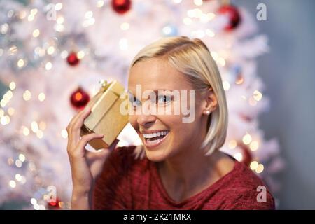 Ich hoffe, es ist nicht zerbrechlich. Porträt einer lächelnden jungen Frau, die ein Geschenk an ihr Ohr hält. Stockfoto