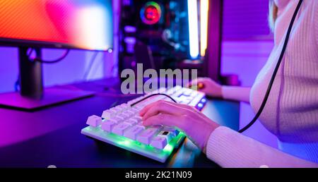 Nahaufnahme Gamer Hände aktiv drücken Tasten mit bunten Neon-LED-Lichter, Frau Kerl tippen auf seine Gaming-Tastatur und Maus zu spielen etwas Spiel in Stockfoto