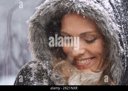 Liebe den ersten Schneefall. Eine attraktive Frau, die sich draußen im Schnee genießt. Stockfoto