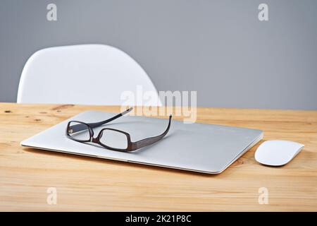 Bequem kabellos. Ein Laptop und eine Brille auf einem Tisch. Stockfoto