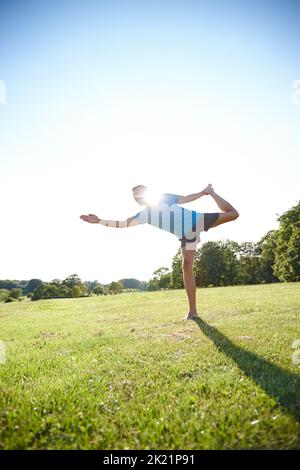 Yoga ist die Poesie der Bewegung. In voller Länge ein hübscher reifer Mann, der im Freien Yoga macht. Stockfoto