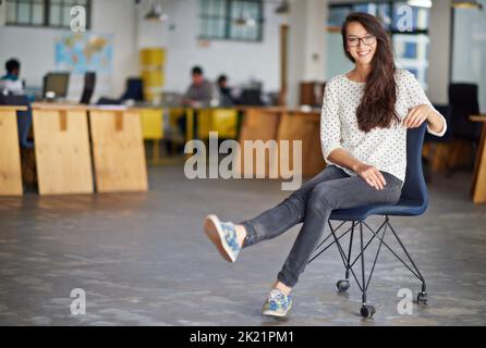 Unser Büro ist kühl. Porträt einer attraktiven jungen Frau, die in einem Büro sitzt. Stockfoto