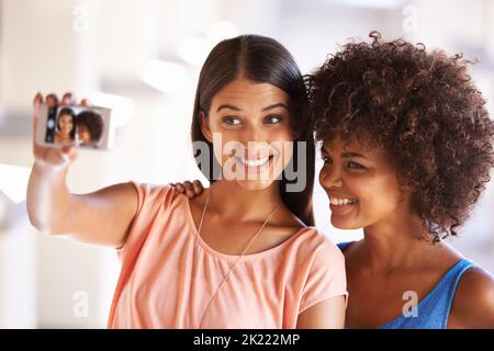 Alle lächeln, wenn Freunde abhängen. Zwei Freundinnen machen ein Selfie auf einem Handy. Stockfoto