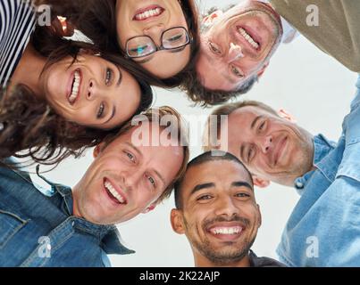 Gemeinschaft gleichgesinnter Menschen. Aufnahme aus dem niedrigen Winkel von sechs Personen, die ihre Köpfe in einem Kreis zusammenfügen. Stockfoto
