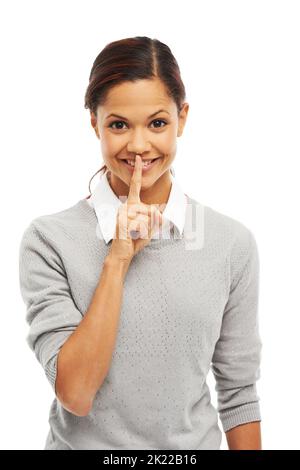 Ich kann gut Geheimnisse bewahren. Studioportrait einer attraktiven jungen Frau mit dem Finger auf den Lippen isoliert auf Weiß. Stockfoto