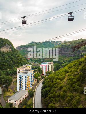 Luftaufstieg Seilbahn mit Metalleimern mit Last über der Straße im Bergbaugebiet in Chiatura. Transportbehälter. Konzept der Kabelbahn. Transpor Stockfoto