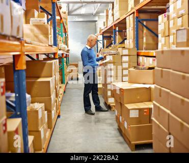 Eingetaucht in seine Aufgabe. Ein Mitarbeiter, der eine Inventarkontrolle in einem Lager macht. Stockfoto