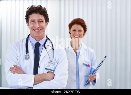 Erfolgreicher Tag der Impfungen. Zwei glückliche Ärzte stehen in einer Klinik zusammen. Stockfoto