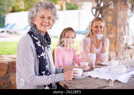 Diese Mädchen lieben ihren Tee. Drei Generationen der Frau der Frauen einer Familie, die draußen Tee trinken. Stockfoto