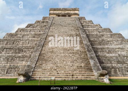 Blick vom Gras auf die Haupttreppen des El Castillo (Tempel des Kukulkan) in Chichen Itza mit blauem Himmel Stockfoto