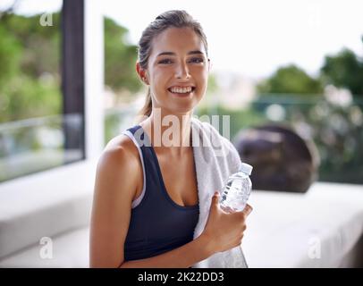 Abkühlung mit mineralischer Güte. Porträt einer attraktiven jungen Frau, die sich nach dem Training entspannt. Stockfoto