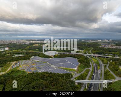 Luftaufnahme von dunklen Sturmwolken über Paneelen auf einem kleinen Solarpark neben der Autobahn Stockfoto