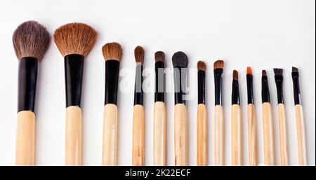 Die Werkzeuge des Make-up-Handels. Eine Reihe von Make-up-Bürsten vor weißem Hintergrund verteilt. Stockfoto