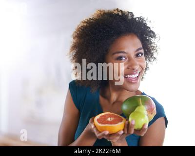 Ihre tägliche Dosis an Vitaminen. Draufsicht auf eine schöne junge Frau, die Ihnen eine Auswahl an frischen Produkten anbietet. Stockfoto