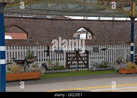 Eine Ausstellung von Blumen und Schafsblumentöpfen mit einem Welcome to Cumbria-Schild am Penrith Railway Station, Cumbria, Großbritannien, 2022. August Stockfoto