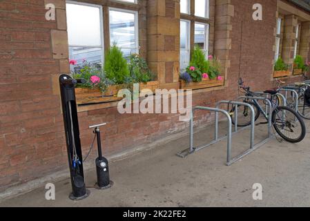 Ein Fahrradparkplatz mit öffentlichen Reparaturwerkzeugen und Fahrradreifenpumpe am Bahnhof Penrith, Cumbria, Großbritannien, August 2022 Stockfoto