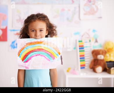 Dont Sie lieben nur die Farben. Ein kleines Mädchen hält ein Bild, das sie von einem Regenbogen gemalt. Stockfoto