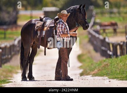 Es gibt nichts Besseres als die Verbindung zwischen einem Mann und seinem Pferd. Ein Cowboy und sein Pferd auf der Ranch. Stockfoto