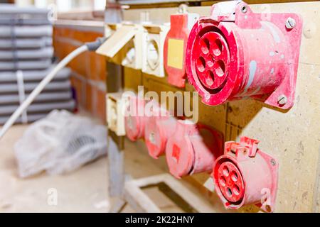 Nahaufnahme des Verteilertabels mit industriellen mehrphasigen Netzsteckern und -Buchsen liefern elektrische Energie für die Baustelle. Stockfoto