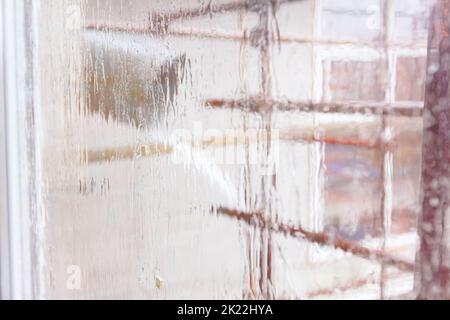 Wasserablauf, provisorische Rinne an einem Wohngebäude, Regen ergießt sich durch das Fenster des im Bau befindlichen Wohngebäudes. Stockfoto