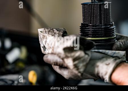 Hände eines Reparaturwerkers, der einen verschmutzten Autoölfilter hält Stockfoto