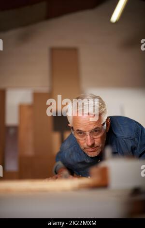 Hes ein Zimmermeister. Ein reifer Zimmermann, der in seiner Werkstatt an einem Projekt arbeitet. Stockfoto