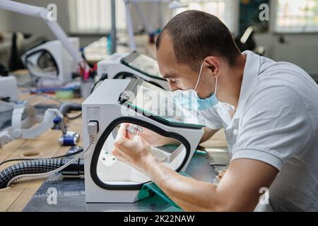 Zahnarzt Hand Mühlen Zahnkronen auf 3D Drucker für Metall erstellt. Zahntechniker, der im Labor mit Keramikkronen in einer Schutzbox arbeitet. Stockfoto