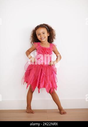 Ich bin eine Märchenprinzessin. Porträt eines kleinen Mädchens in einem rosa Kleid, das die Kamera anlächelt. Stockfoto