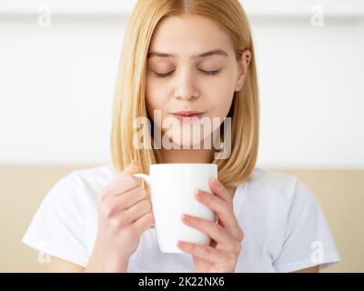 Kaffee Entspannen. Morgentee. Fauler sonntag. Tag frei. Freizeit zu Hause. Friedlich zufrieden lächelnd junge hübsche Frau in angenehmer Stimmung genießen Tasse aromatisch Stockfoto