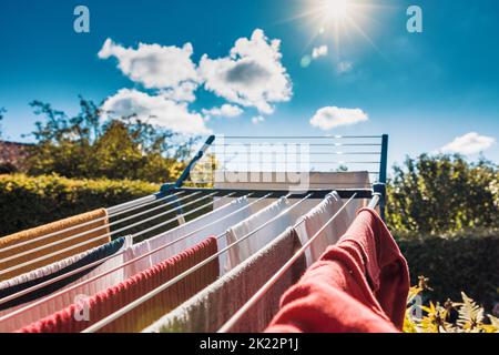 Trocknen Sie nasse Wäsche nach der Wäsche auf einem Trockengestell im Sommer in der Sonne, um Energie zu sparen, indem Sie keinen elektrischen Trockner verwenden. Stockfoto